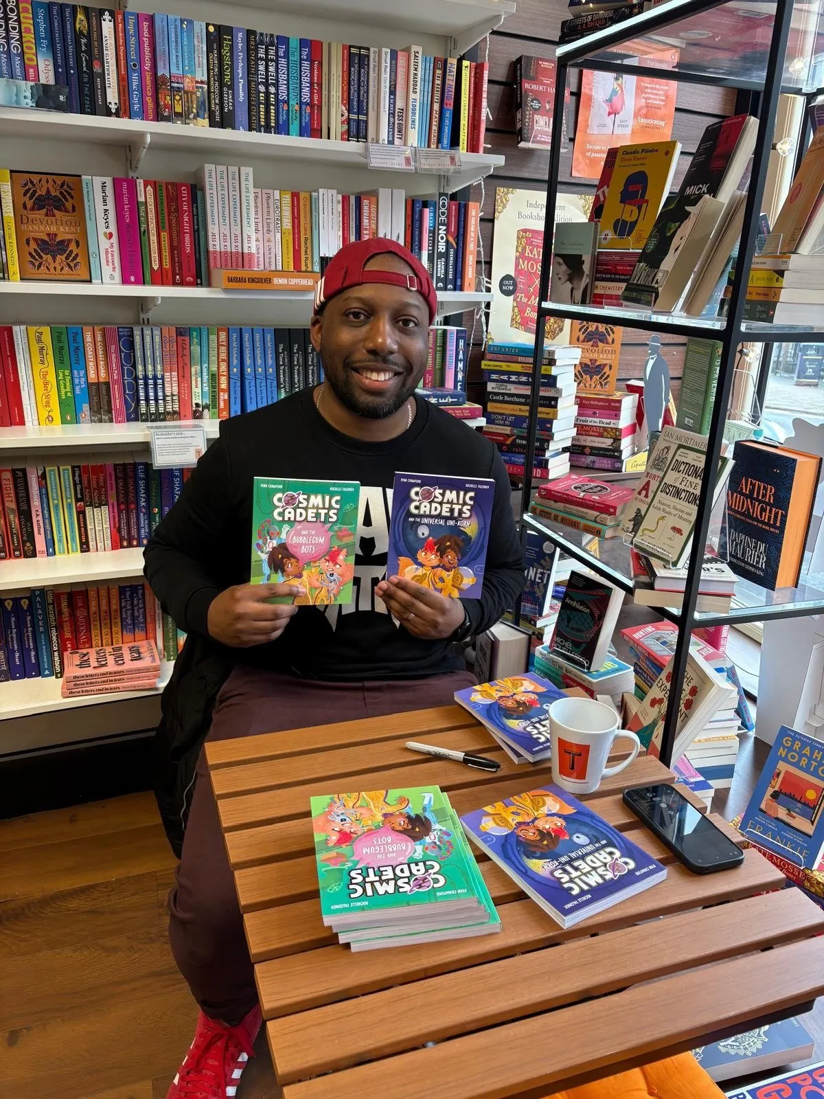 Ryan Crawford at a bookshop table holding both Cosmic Cadets titles